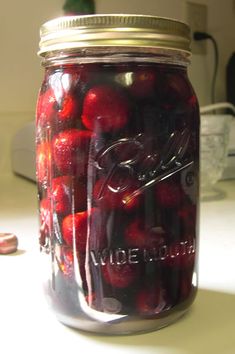 a jar filled with cherries sitting on top of a table