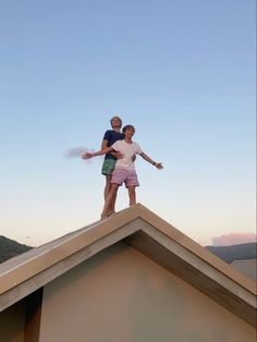 a man and woman standing on top of a roof