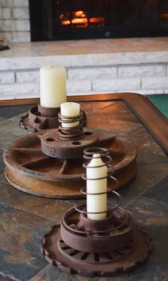 two candles sitting on top of a table next to a fire place in front of a fireplace