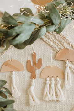 three wooden ornaments are hanging on a wall next to some plants and greenery with leaves