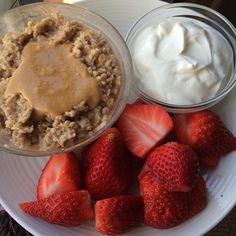 a plate topped with oatmeal and strawberries next to yogurt