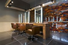 a room with some chairs and lights on the wall next to a counter in front of a mirror