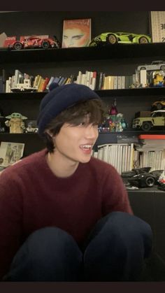 a young man sitting in front of a book shelf