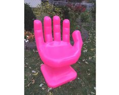 an inflatable pink hand sitting on top of a lush green field