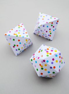 three white paper balls with multicolored dots on them