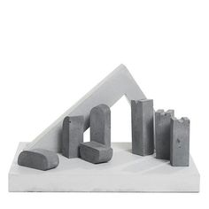 a sculpture made out of concrete blocks on top of a white surface with one block in the shape of a house