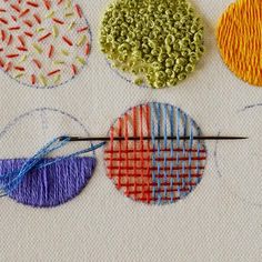 four different types of embroidery on a piece of fabric with needles and thread in the middle