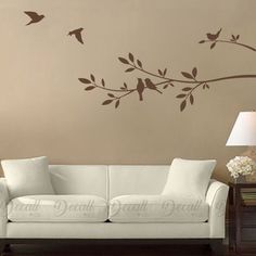 a living room with a white couch and brown wall decal