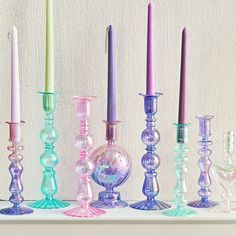 there are many different colored glass candles on the shelf in front of each other,