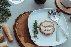 a white plate topped with a wooden slice next to utensils