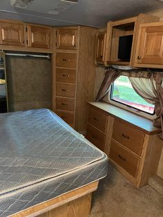 a bedroom with a bed, cabinets and a window in the back wall is shown