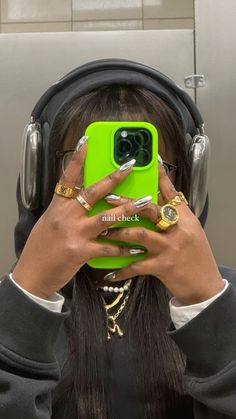 a woman wearing headphones and holding her phone up to her face with both hands