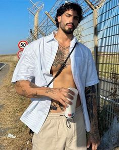 a man standing next to a fence holding a coffee cup