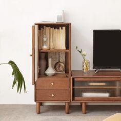 an entertainment center with bookshelf, television and vases on the top shelf