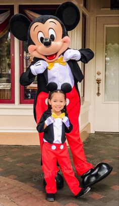 a little boy standing next to a mickey mouse mascot