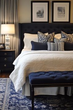 a bed with blue and white pillows on top of it next to two framed pictures