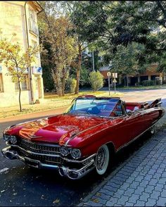 an old red car is parked on the side of the road