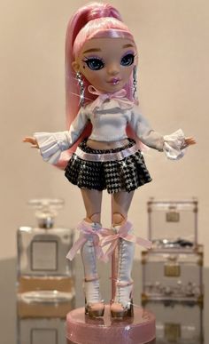 a doll with pink hair is standing on a pedestal