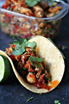 an open tortilla with meat and vegetables on it next to a bowl of salsa