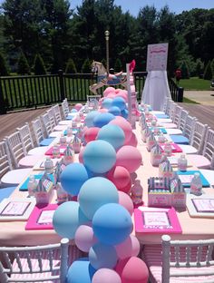 a table set up for a birthday party with pink, blue and white balloons on it