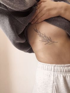 a woman with a tattoo on her stomach holding onto the back of her body and wearing sweatpants