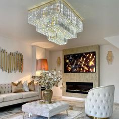 a living room filled with furniture and a large chandelier above the fire place