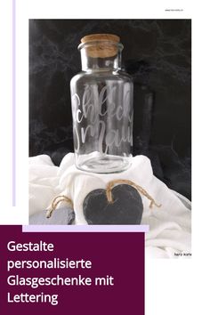 Glasgeschenk mit Aufschrift "Schleckmaul", dekoriert auf weißem Stoff mit Herzanhänger.