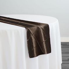 a white table topped with a brown satin table runner