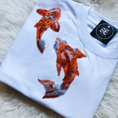 an orange and white t - shirt with sequins on the front is laying on a furry surface