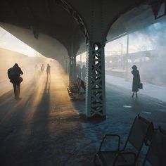 people are walking in the fog under an overpass