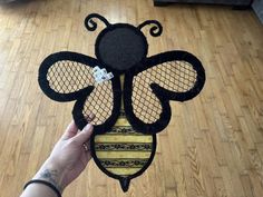 a person holding up a piece of art that looks like a bee on the floor