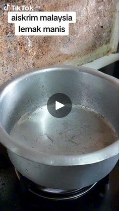 a metal bowl sitting on top of a stove next to a brick wall with the words askkim malaysia lemak maniis