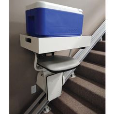 a cooler sitting on top of a stair case next to a hand rail and carpeted stairs