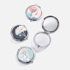 three compact mirrors with floral designs on them