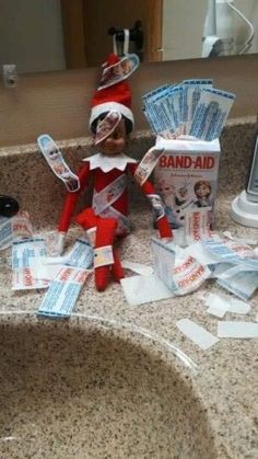 an elf is sitting on the bathroom sink with some bills in front of him,