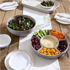 a table topped with bowls filled with different types of vegetables and fruit next to white plates