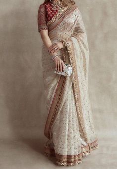 Off white/ cream heavy embroidered saree, Festive wear saree with embroidered borders and embellished gold blouse. This sari is a custom made garment which includes the saree and the blouse. Saree material is net and the blouse has sequins embroidery. It can be customised in any color of your choice. Upon order confirmation, we will send you a measurement form which you will need to fill in inches, so that it can made to your size. Care- Dry clean only. There might be slight variation in the color of the product and the design due to digital photography and different computer resolutions. Saree Wearing Styles, Simple Saree Designs, Sari Design, Perhiasan India, Indian Bride Outfits, Fashionable Saree Blouse Designs, Fancy Sarees Party Wear, Indian Saree Blouses Designs, Chique Outfits