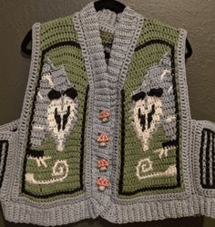 a crocheted vest hanging on a wall with an image of a wolf in the middle