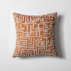 an orange and white pillow on a white wall