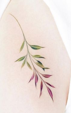 the back of a woman's shoulder with green and purple leaves tattoo on it