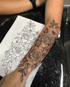 a woman's arm with flowers on it and a drawing in the back ground