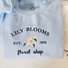 Lily Blooms Floral Shop Embroidered Sweatshirt, Book Merch Sweatshirt, Coho Crewneck, It Ends With Us, It Starts With Us, Flower Hoodie, These Gildan 18000 sweatshirts are likely to become your new favorite! Super soft & lightweight. What more could a girl ask for, right? How about a spectacular message to help you put out into the world? We have you covered there, too! We use the best quality print material. Ideal for any situation, a unisex heavy blend crewneck sweatshirt is pure comfort. Thes Sweater Merch Ideas, Printed Hoodies Ideas, It Starts With Us, Flower Hoodie, Book Merch, Clothing Business, Girls Ask, Lily Bloom, Xmas List