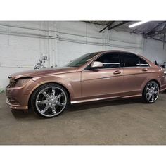 a brown car parked in a garage next to another car with wheels on the rims