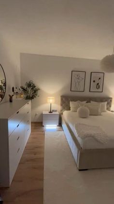 a large white bed sitting in a bedroom next to a dresser and lamps on either side of the bed