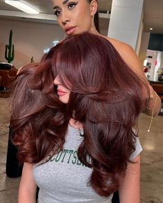 Embrace the season's warmth with this radiant auburn hair color that brings a burst of freshness to your look. Perfectly styled with voluminous waves, the hairstyle exudes a playful yet refined charm ideal for both casual brunches and elegant evening affairs. The deep red hue paired with lush, flowing curls is a stunning choice for anyone looking to make a statement this spring. / Photo Credit: Instagram @maggiemh Red Hair Color With Brown Hair, Chocolate Brown Hair With Violet Undertones, Chocolate Brown Reddish Hair, Blonde Burgundy Brown Hair, Dark Cherry Brown Hair Curly, Raspberry Chocolate Hair Color, Red Toned Brunette Hair, Chocolate Burgundy Hair Color, Red Hair For Black Hair