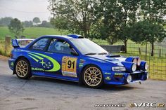 a blue race car parked in front of a fence