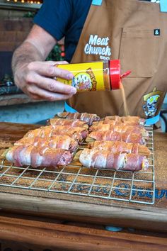 a person pouring ketchup onto some food on top of a metal rack in front of an oven