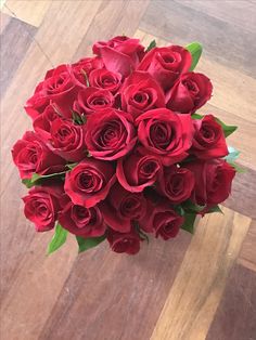 a bouquet of red roses sitting on top of a wooden floor