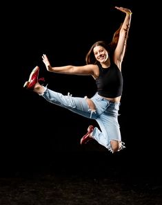 a woman is jumping in the air with her legs spread out and one leg up