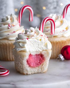 two cupcakes with white frosting and candy canes